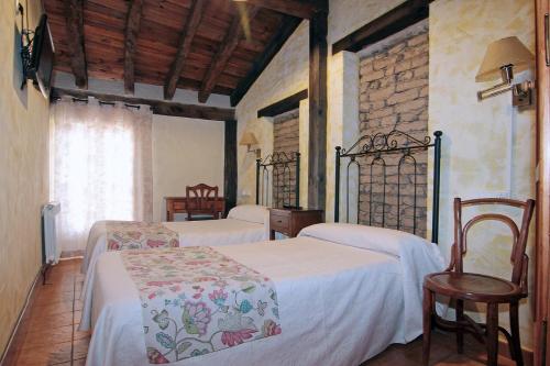 Montemayor de PilillaHOTEL RURAL LOS ABUELOS的一间卧室设有两张床、一把椅子和一个窗户。