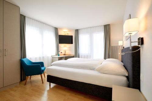 布鲁嫩Hotel Schmid & Alfa的酒店客房,配有一张床和一张蓝色椅子