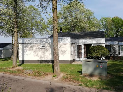 辛佩尔费尔德Rustige, gelijkvloerse vakantiewoning met 2 slaapkamers in Simpelveld, Zuid-Limburg的前面有一棵树的白色房子