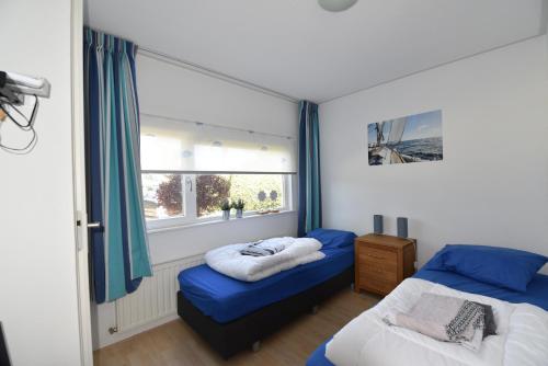 RohelVakantiehuis Tjeukemeer, de Friese Meren的一间卧室设有两张床和窗户。