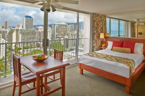 檀香山Pacific Monarch Hotel的一间卧室配有一张床、一张书桌和一个大窗户