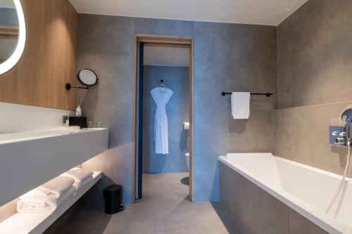 兰斯贝斯特韦斯特普瑞米尔派克斯酒店 的浴室设有白色浴缸和一身男子气概的连衣裙