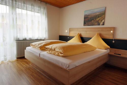 WehingenHotel Heuberger Hof, Wehingen的一间卧室配有一张带黄色枕头的床。