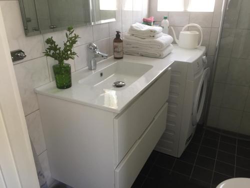 法尔雪平Stenbrottets lillstuga的白色的浴室设有水槽和镜子
