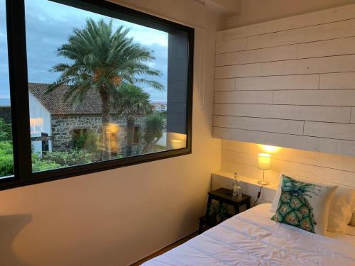 蓬塔德尔加达2Azores With Comfort and Style的一间卧室设有一扇带棕榈树的大窗户