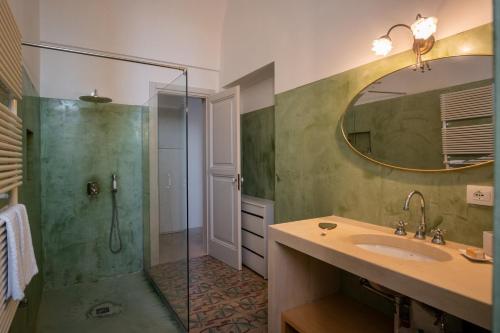 马利耶Palazzo Garzia Residence - Dimora storica的带淋浴、盥洗盆和镜子的浴室