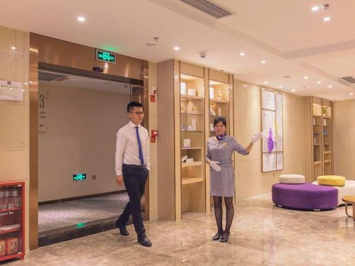 渝北麗枫酒店·重庆江北国际机场中心店的两个男人和一个女人站在大厅里