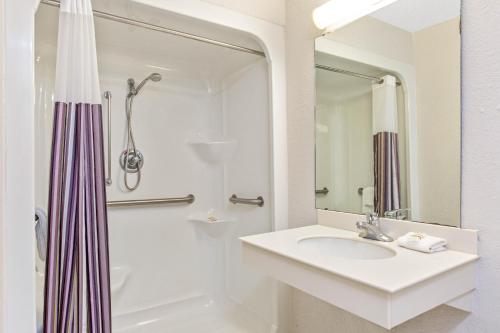 斯莱德尔Quality Inn Slidell I-10的白色的浴室设有水槽和淋浴。