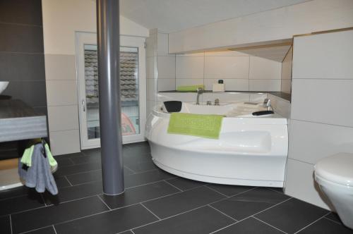 Lichtensteig目的地汽车旅馆的带浴缸、卫生间和盥洗盆的浴室