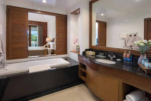 北碧Dheva Mantra Resort的一间带浴缸和大镜子的浴室
