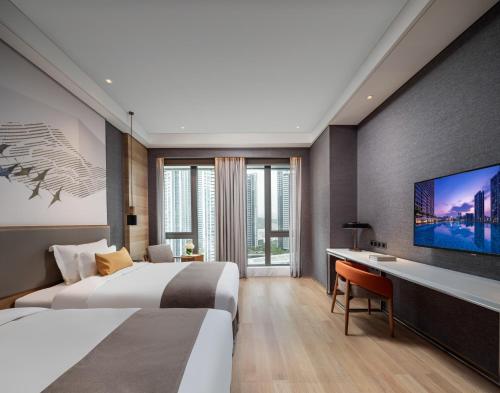 深圳深铁塘朗城君璞酒店的酒店客房设有两张床和一台平面电视。