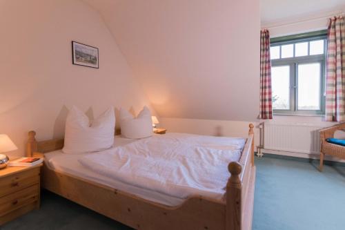 欧巴德伍斯图Ferienhaussiedlung Strandperlen Küstenhof 2b (Typ V)的一间卧室配有一张带白色床单的床和一扇窗户。