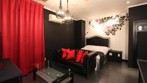 宇都宫雷斯特太阳城酒店（仅限成人）的一间卧室配有沙发和一张带红色枕头的床