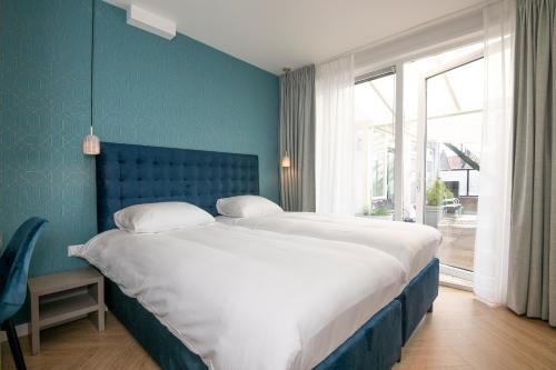 诺德韦克皇家酒店的一间卧室设有一张大床和蓝色的墙壁