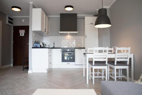 马尔堡Apartament Scandic的厨房配有白色橱柜和桌椅
