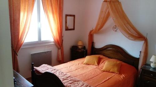 布尔圣昂代奥l'oustau bonur的一间卧室配有带橙色床单的床和窗户。