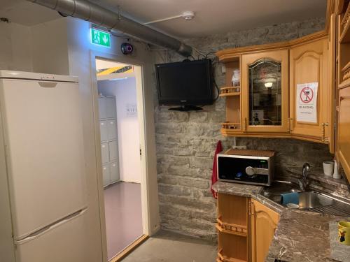 塔林Süda Hostel的带冰箱的厨房和墙上的电视