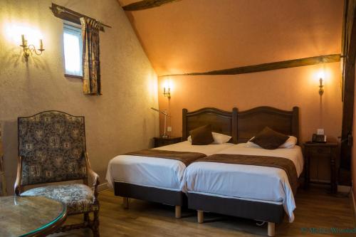 Ligny-le-ChâtelLOGIS HOTEL - Le Relais Saint Vincent的一间卧室配有两张床、一张桌子和一把椅子