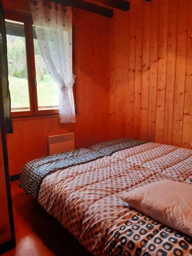 拉穆拉CHALET LES EPILOBES的木制客房的一张床位,设有窗户