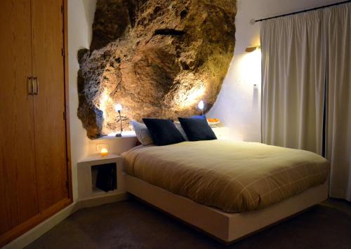 蒙地卡罗拉洛卡度假屋的一间卧室配有一张带岩石墙的床