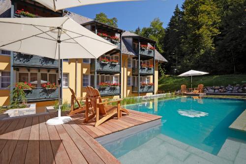 欣特察尔滕贝弗雷德公寓式酒店的一个带两把椅子和遮阳伞的游泳池