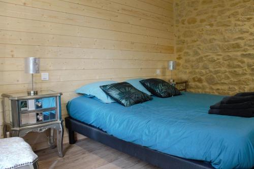 萨尔拉拉卡内达chambres d’hôte le breuil的一间卧室配有一张蓝色的床和木墙