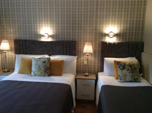 基拉尼花园食宿酒店的配有2盏灯的酒店客房的2张床
