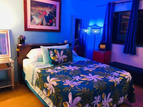科纳科纳马吉克霍努民宿的蓝色的卧室,配有一张带彩色毯子的床