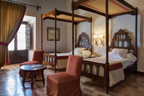 乌贝达乌贝达旅馆的一间卧室设有两张天蓬床和一把椅子