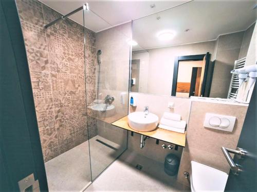 萨拉热窝Orange Hotel的一间带水槽和玻璃淋浴的浴室