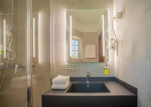 贝林佐拉尤念恩酒店的浴室配有盥洗盆和带镜子的淋浴