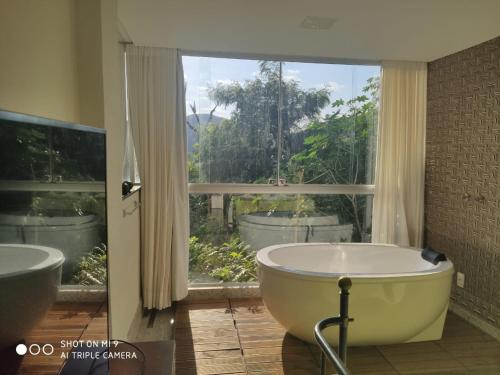 新利马Loft Espaço Vila da Serra的带浴缸的浴室和大窗户