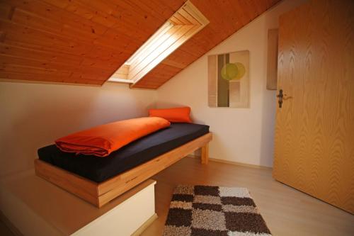 拉姆斯泰因-米森巴赫Ferienwohnung Ramstein的小卧室配有带橙色枕头的床
