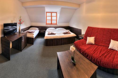 KameniceŠtiřínská stodola u Prahy的客房设有两张床、一张沙发和一台电视。