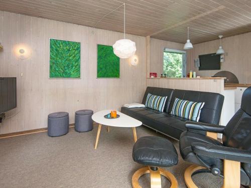 博利尔马克6 person holiday home in R m的客厅配有黑色沙发和桌子