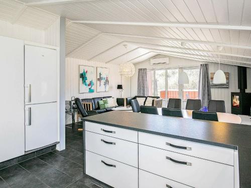 瓦伊厄斯斯特兰德8 person holiday home in Vejers Strand的厨房以及带白色橱柜和椅子的用餐室。
