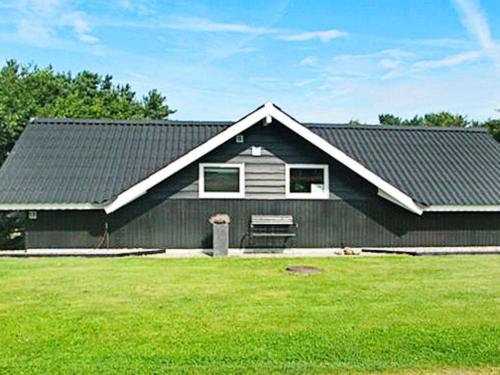 安斯艾厄6 person holiday home in Ansager的前面有绿色草坪的黑色房子
