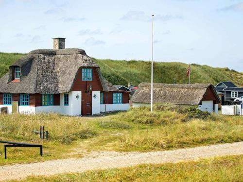 法贾德嘉德5 person holiday home in Ulfborg的路边茅草屋顶的房子