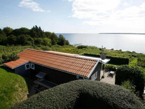 森讷比4 person holiday home in Juelsminde的水边有红色屋顶的小房子