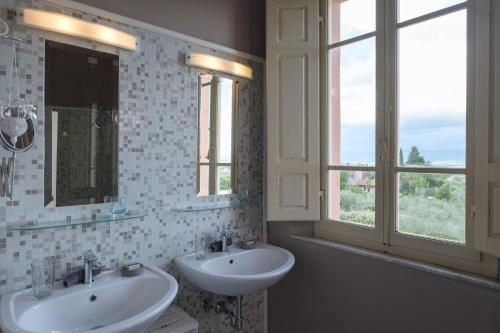 PozzoFontelunga Hotel & Villas的一间带两个盥洗盆和两个窗户的浴室