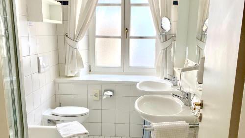 明德尔海姆Hotel Alte Post的白色的浴室设有两个盥洗盆和窗户。
