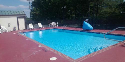 阿卡德尔菲亚Baymont by Wyndham Caddo Valley/Arkadelphia的一个带椅子和桌子的大型蓝色游泳池