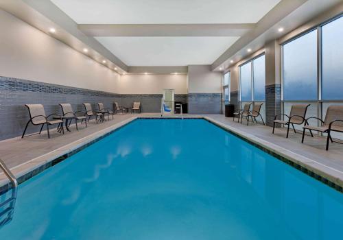路易斯维尔La Quinta Inn & Suites by Wyndham Lewisville的大楼内带桌椅的大型游泳池