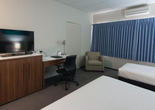 杰拉尔顿海洋中心酒店的酒店客房配有一张床和一张书桌及一台电视