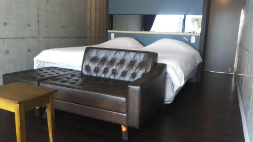 座间味村Blue Suites Hanamuro的一间卧室配有一张床和一张皮椅