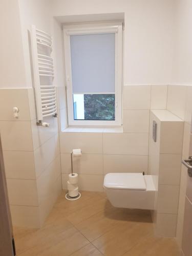 卡尔帕奇Apartamenty KADO的白色的浴室设有卫生间和窗户。