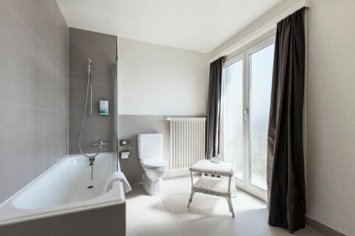 洛桑贝勒里夫酒店的带浴缸、卫生间和窗户的浴室