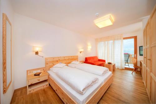 帕尔奇内斯Hotel Niedermair的卧室配有一张白色大床和一把椅子