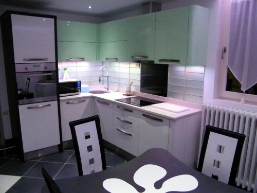 茹瓦尼Grand appartement dans villa avec parking quartier résidentiel的厨房配有绿色橱柜和桌椅