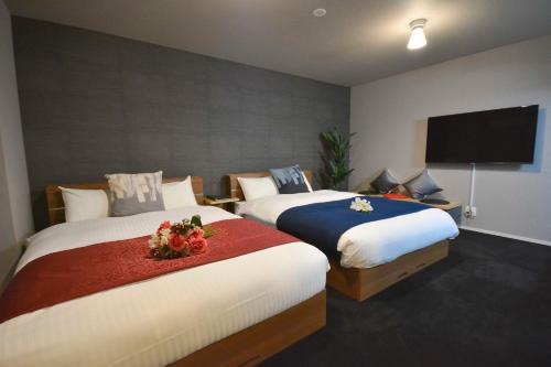 福冈The Grand Residence Hotel Tenjin的一间卧室配有两张床和一台平面电视